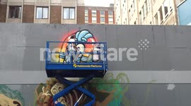 Street artist working on cherry picker