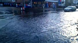 cars drive through flood in front of petrol station in Egham