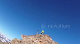 Man throws rock at drone on mountain peak