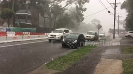 Cars driving through rain , hail storm and flooded road
