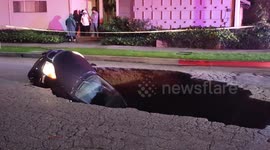 Sinkhole swallows two cars with driver still inside.