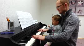 Adorable one-year-old baby plays piano with her dad