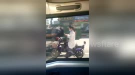 Daredevil woman plays with phone while driving scooter