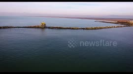 Aerial shot of some fishermen houses with huge nets outside situated in the middle of the sea, in Tuscany, Italy, filmed with drone, 4K