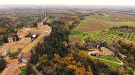 Aerial shot, a small ancient town Bolgheri situated in the middle of rural landscape with cultivated field and a lot of olive trees in Tuscany, Italy, shot with drone, 4K