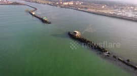Aerial shot of some fishermen houses with huge nets outside situated in the middle of the sea, in Tuscany, Italy, filmed with drone, 4K