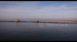 Aerial shot of some fishermen houses with huge nets outside situated in the middle of the sea, in Tuscany, Italy, filmed with drone, 4K
