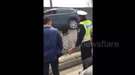 江苏一司机为避让三轮车 驾车飞上三米高屋顶