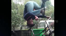Chinese martial artist rides bike while doing a head stand