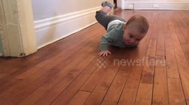 Baby learning to crawl tries his hardest to get a toy