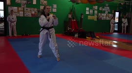 Slow motion video of an adult taekwondo training session in the gym, a woman kicking, selective focus