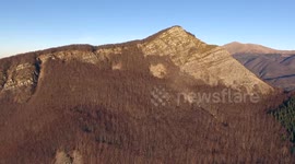 Aerial shot, autumn landscape in the high mountains in Italy with coniferous wood, sun high in the sky, filmed with drone, 4K