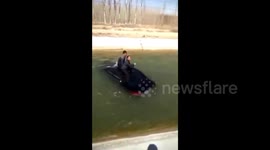 Car with two men on roof drifts on canal