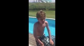 Young boy jumping through donut ring in water