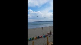 A Couple of Military Helicopters Training Their Stunts Above The Sea