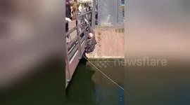 Man reaches under bridge to retrieve fishing magnet
