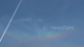 The plane flies past the rainbow cloud