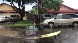 Men make the most of a flood and have an impromptu surfing session