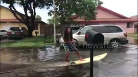 Men make the most of a flood and have an impromptu surfing session