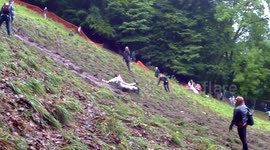 Slow-motion footage of man sliding to bottom of hill in UK cheese-rolling race