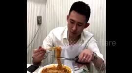 Chinese man uses scissors to shorten noodles while eating