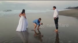 Freak wave knocks bride over on beach during photo shoot