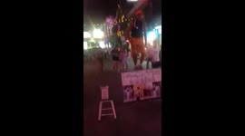 Man stands on the street in extreme heat of 35 degrees in thailand doing kick ups with a golf ball using two golf clubs.