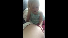 little girl feeling baby kick in her mom's belly.  Her reaction is priceless.