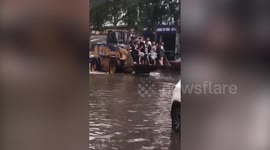 Digger driver charges two pounds a journey to transport commuters along flooded road