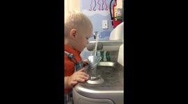 Toddler gets all wet trying to get a drink from water fountain