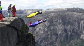 wingsuit BASE jumpers exiting 3000ft high cliff at Heliboogie BASE jumping event in Norway