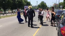 Bulgarian wedding-goers dance on a busy road