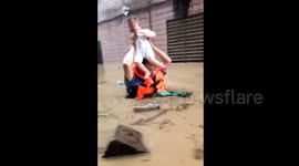 Policeman carries toddler above head to cross flooded road