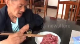 Chinese elderly man eats raw meat