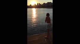 Summer shot - kid jumping to the sea in sunset
