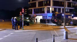 Riot police officers riding on outside of police tank in the city of Hamburg