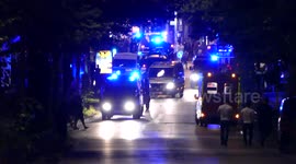 Police vans driving in the distance ahead of other armored police vehicles
