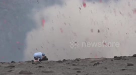 Volcano erupts as man stands next to crater
