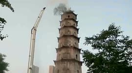 Firemen use crane to water tree growing on top of ancient pagoda