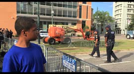 African American teenager watches removal of controversial confederate General E. Lee statue monument by construction crew in Lee Circle. People cheer in the background