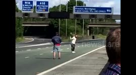 Men play tennis on UK motorway with traffic at standstill