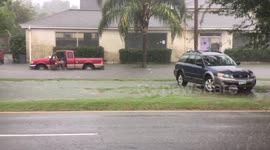 Truck driver enters car to move it during rising flood waters