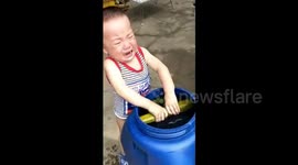 Baby cries when he can't get cucumber out of bucket