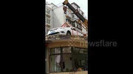 Illegally parked car lifted onto building roof by crane