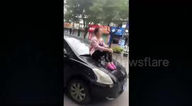 Disgruntled woman sits on hood of husband's moving car