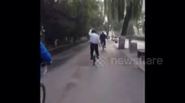 Chinese man does Tai Chi while riding bike on busy road