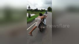 Daredevil motorcyclist skids along road in flip flops