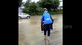 Elderly man carries wife on back to cross flooded road