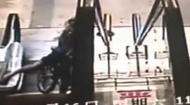 Boy on bike falls down escalator