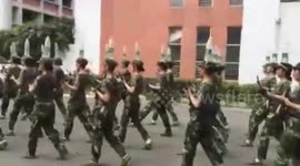 Cadets march while balancing water bottles on their heads